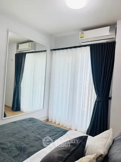 Modern bedroom with large mirror and elegant curtains, featuring a cozy bed and air conditioning.