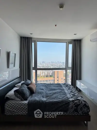 Spacious bedroom with large window offering stunning city view, modern decor, and ample natural light.