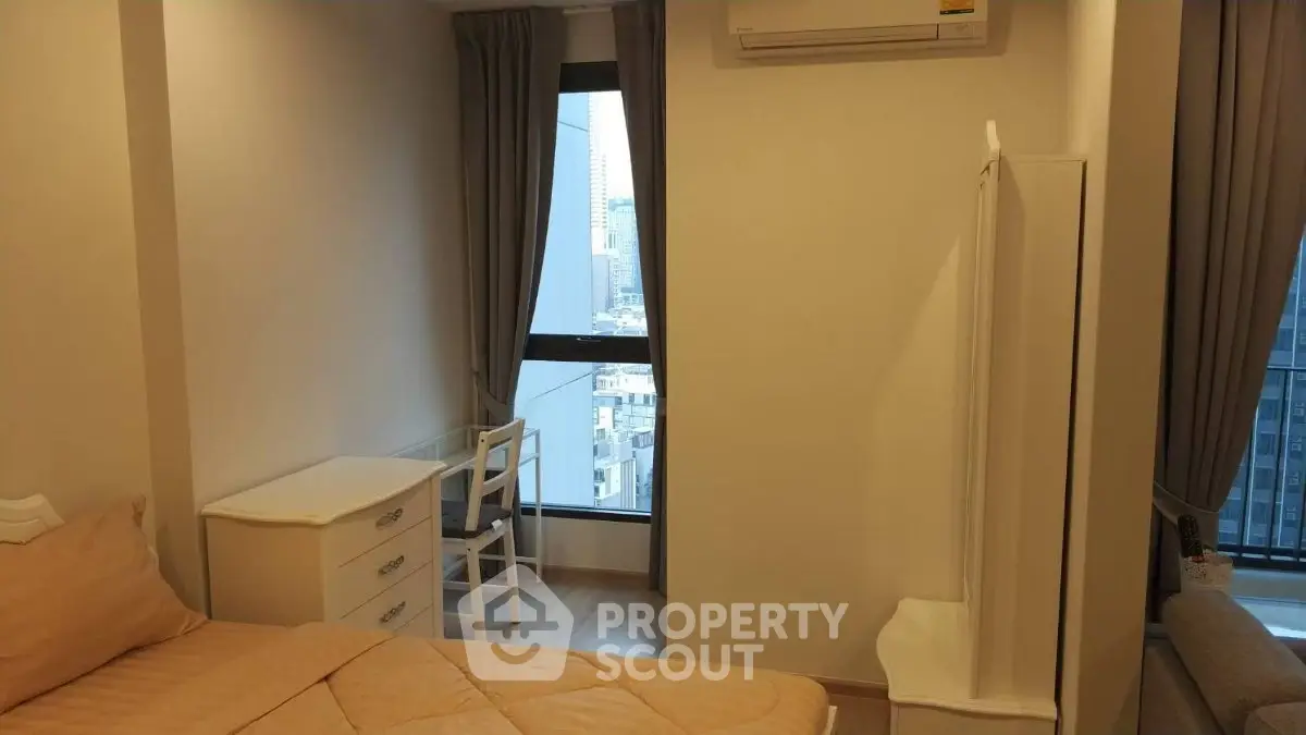 Cozy bedroom with city view, featuring a comfortable bed, desk, and air conditioning.