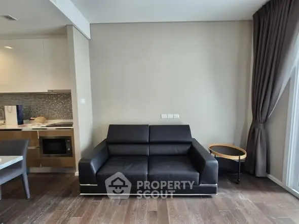 Modern living room with sleek black sofa and open kitchen layout.