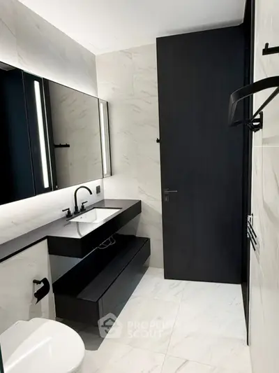 Modern bathroom with sleek black fixtures and marble tiles, featuring a stylish vanity and large mirror.