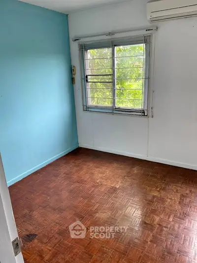 Cozy empty room with wooden flooring and air conditioning, perfect for customization.