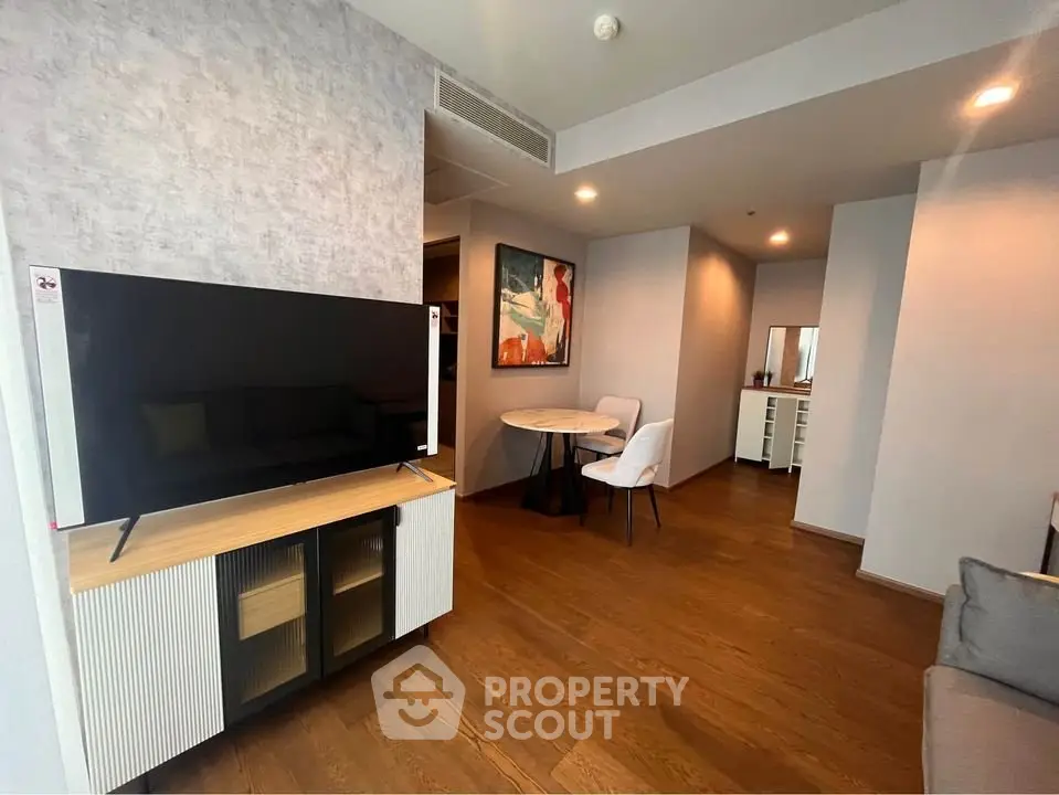 Modern living room with stylish decor and wooden flooring, featuring a TV and cozy dining area.