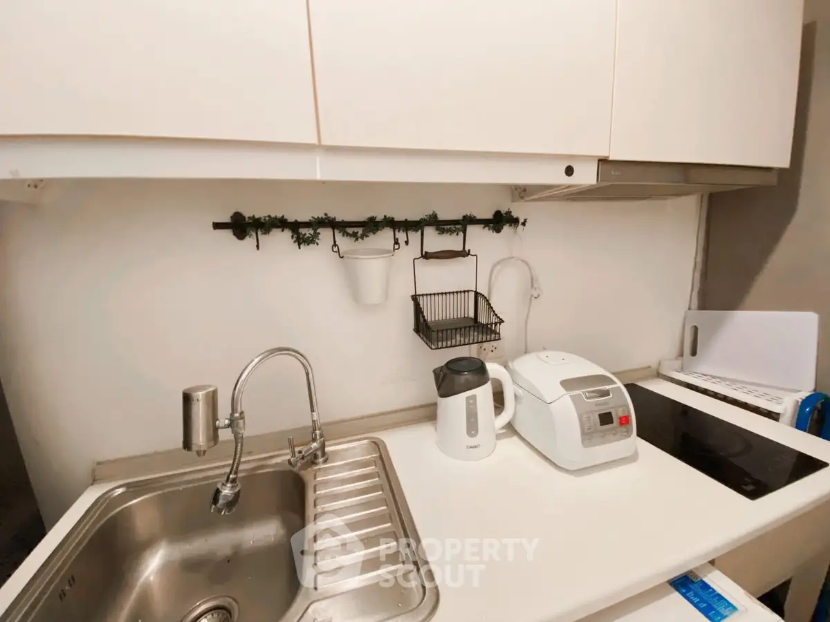 Compact kitchen with modern appliances and sleek white cabinetry.