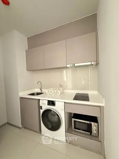 Modern compact kitchen with integrated appliances and sleek cabinetry