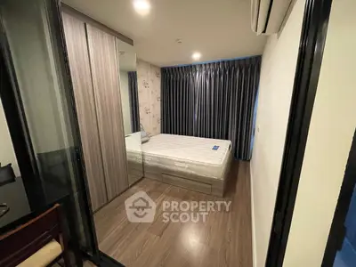 Cozy modern bedroom with wooden flooring and mirrored wardrobe in a stylish apartment.