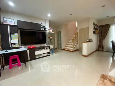 Spacious modern living room with sleek entertainment center and elegant staircase