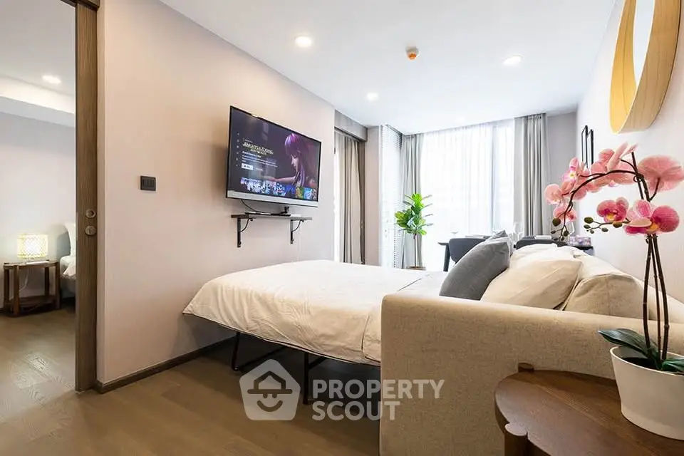 Modern bedroom with wall-mounted TV and elegant decor in a bright apartment.