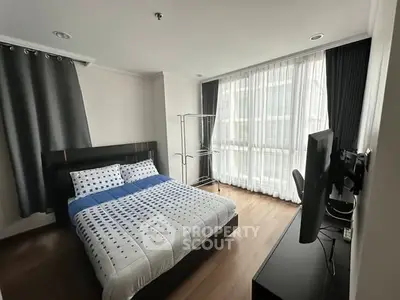 Modern bedroom with large window and stylish decor in a contemporary apartment.