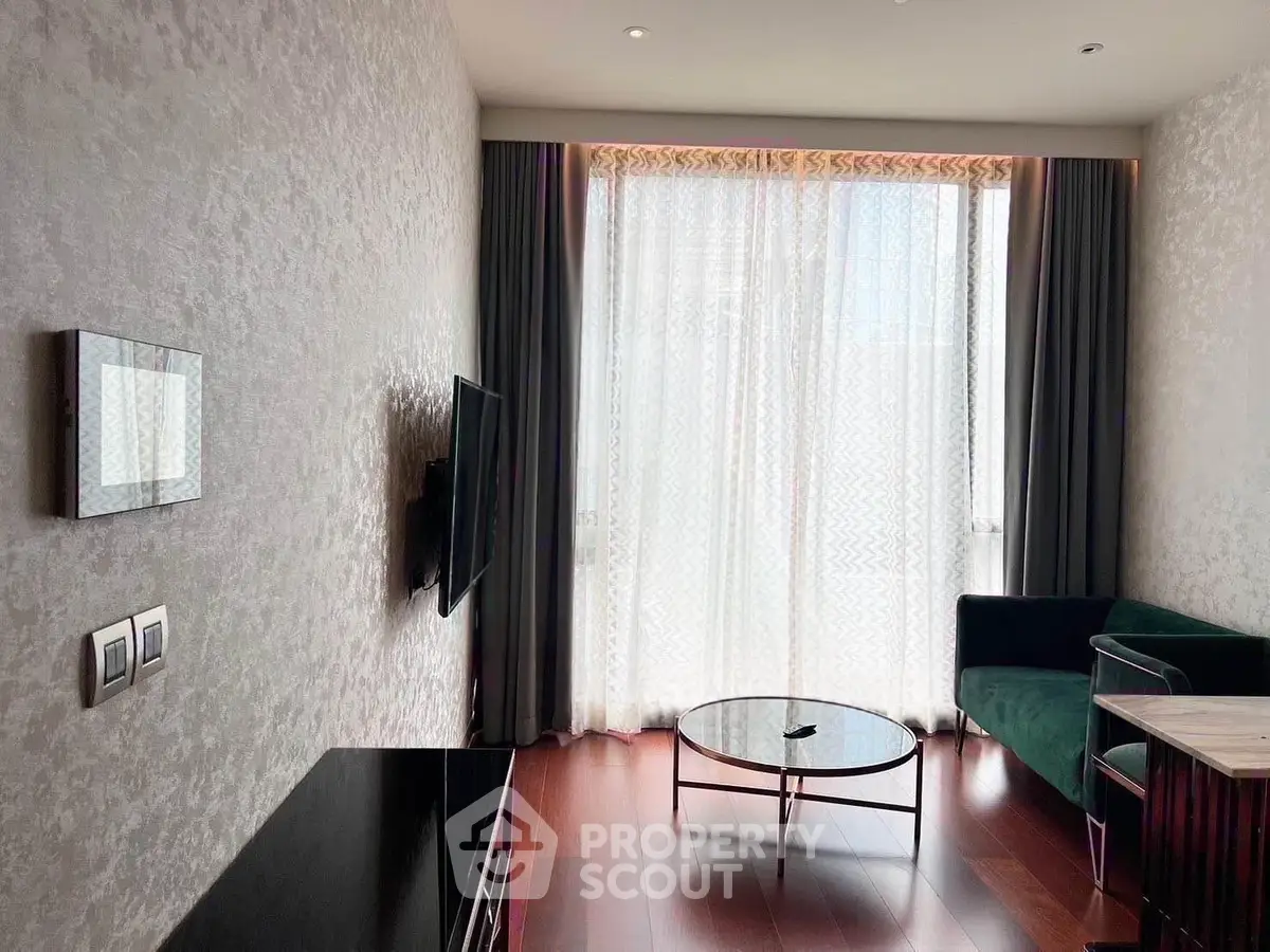 Modern living room with elegant decor and large window, featuring a wall-mounted TV and stylish furniture.