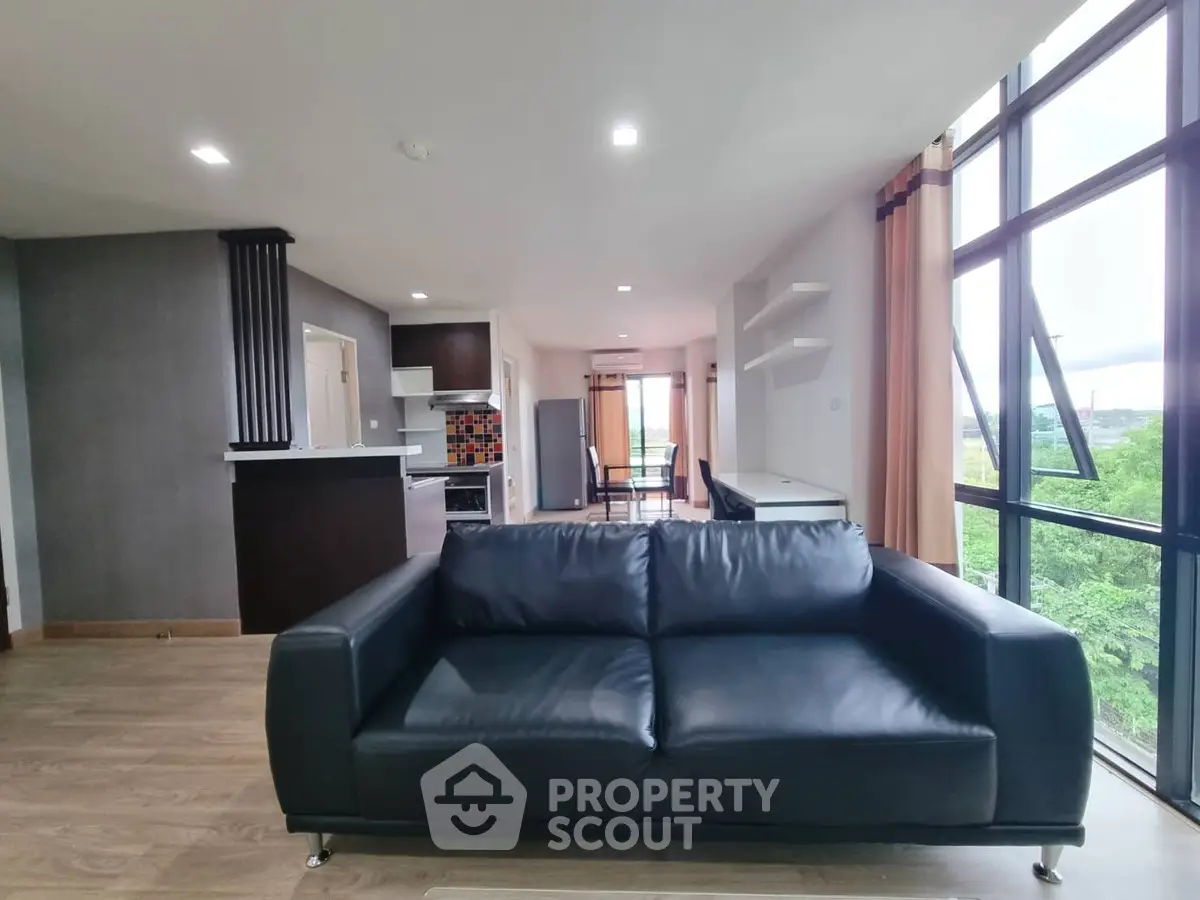 Spacious modern living room with large windows and stylish black sofa