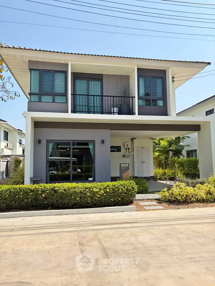 Modern two-story house with balcony and landscaped front yard in a suburban neighborhood.