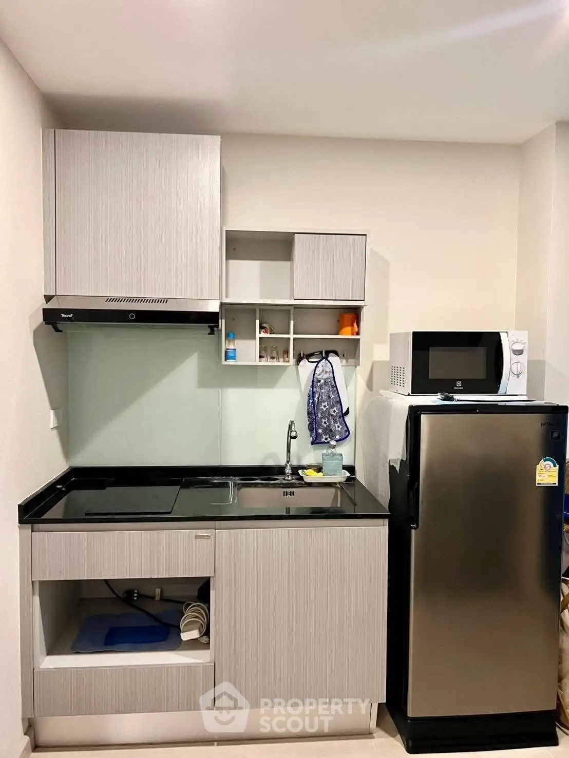 Modern compact kitchen with sleek cabinetry and stainless steel appliances in a stylish apartment.