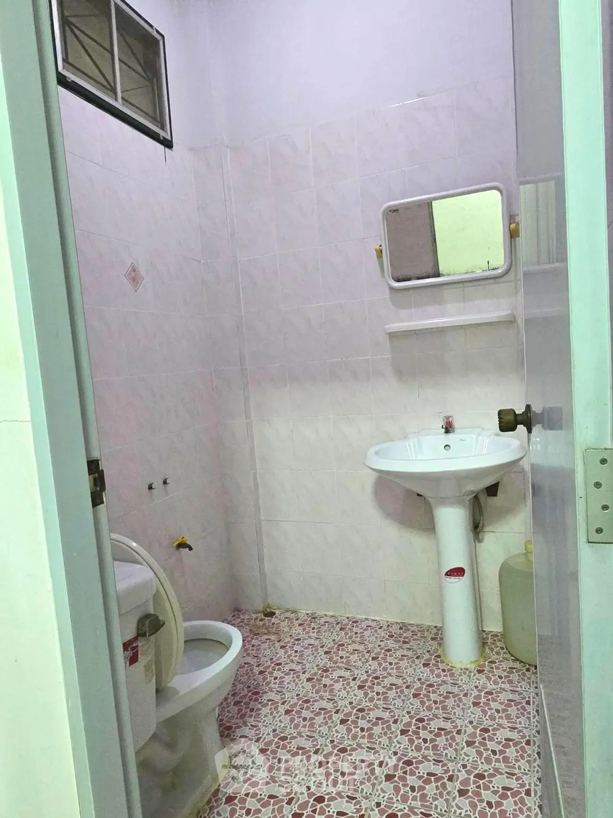 Compact bathroom with pedestal sink and tiled walls, ideal for small spaces.