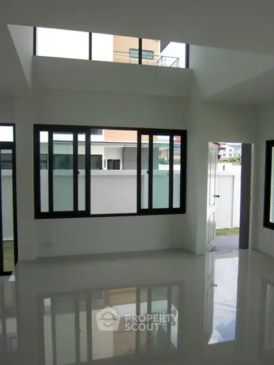 Spacious modern living room with large windows and glossy tiled floor