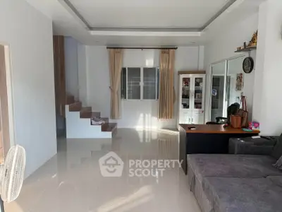 Spacious living room with modern decor and natural light, featuring a cozy sofa and elegant staircase.