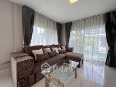 Spacious living room with modern sectional sofa and glass coffee table, featuring large windows and elegant curtains.