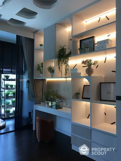 Elegant custom-built shelving unit with integrated lighting in a modern living space, showcasing a tasteful mix of decorative items and greenery.