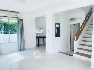 Bright and spacious living room with modern staircase and large window view.
