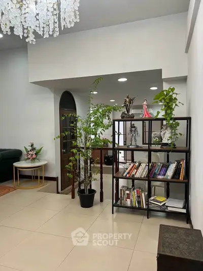 Spacious living room with elegant decor and indoor plants, featuring a stylish bookshelf and modern lighting.