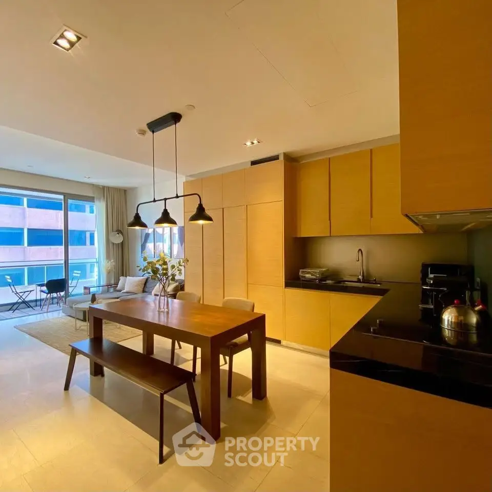 Modern open-layout kitchen and dining area with wooden cabinetry and stylish lighting.