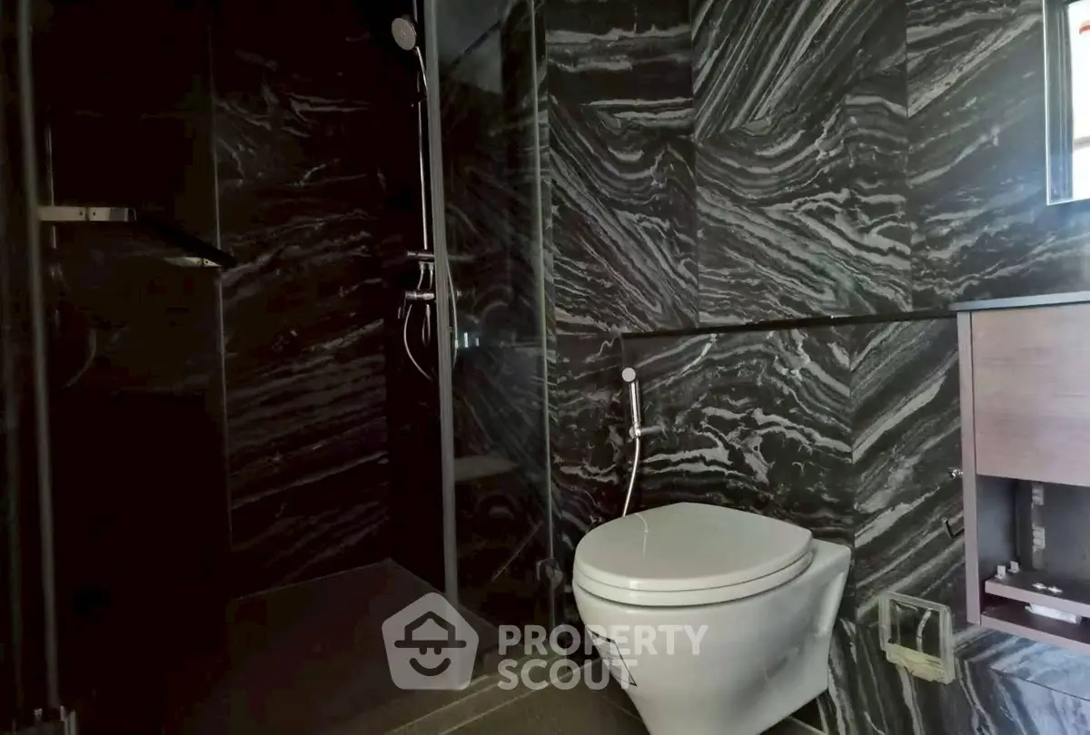 Luxurious modern bathroom with sleek black marble tiles and elegant fixtures.