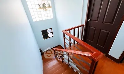 Charming staircase with wooden railing and elegant chandelier in cozy home