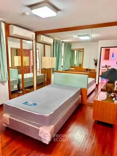 Spacious bedroom with mirrored closets and wooden flooring in modern apartment