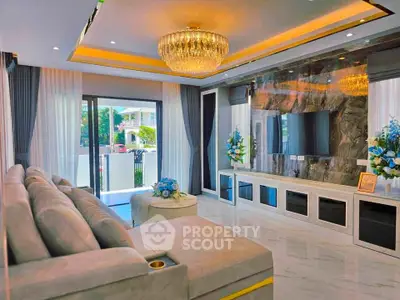 Luxurious living room with elegant chandelier and modern decor, featuring a spacious sofa and large TV.