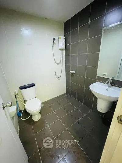 Modern bathroom with sleek tiles and wall-mounted shower in a contemporary apartment.