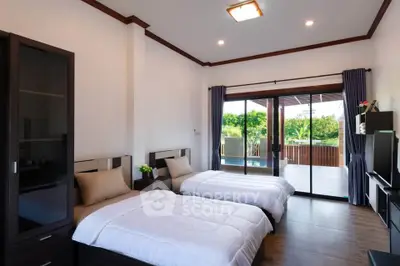 Spacious bedroom with twin beds and large balcony overlooking lush greenery.