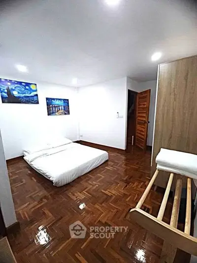 Spacious bedroom with wooden flooring and modern decor in a cozy apartment.