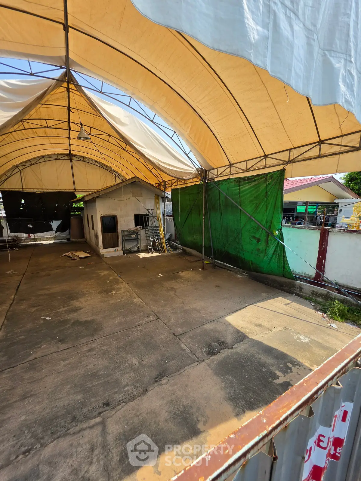 Spacious outdoor area with large canopy, ideal for events or storage, featuring durable flooring and ample space.