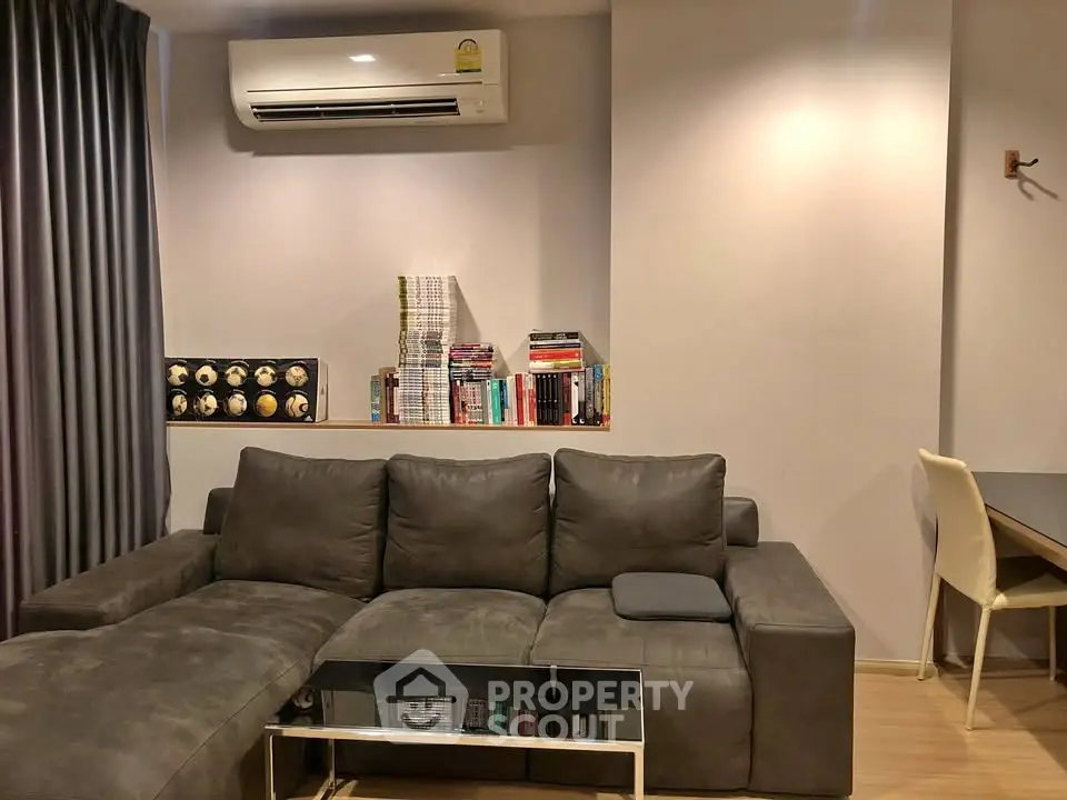 Modern living room with sleek gray sofa, air conditioning, and stylish bookshelf.