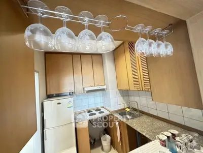 Charming kitchen with wooden cabinets and glass rack, featuring modern appliances and efficient layout.
