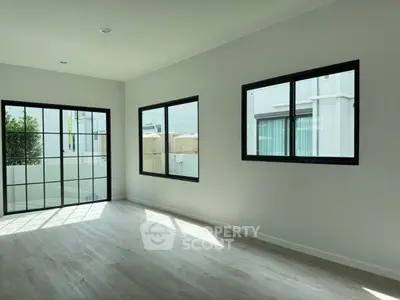 Spacious sunlit room with large windows and modern flooring
