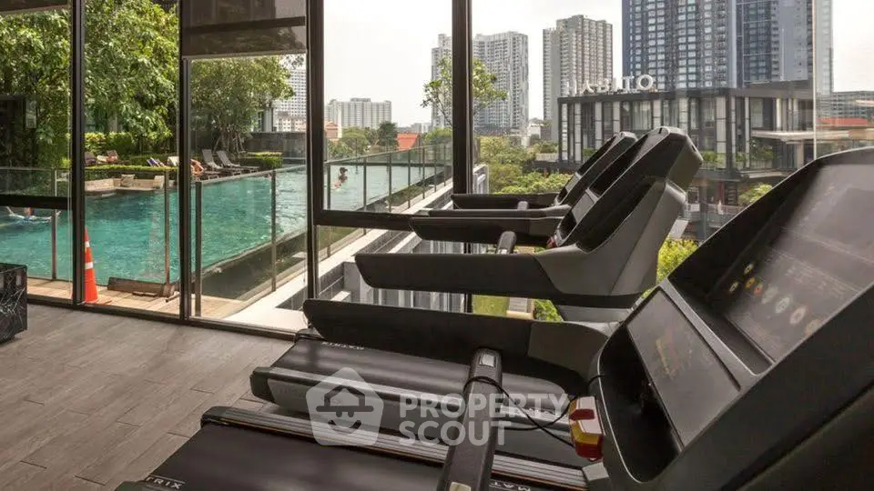 Luxurious gym with pool view in modern high-rise building