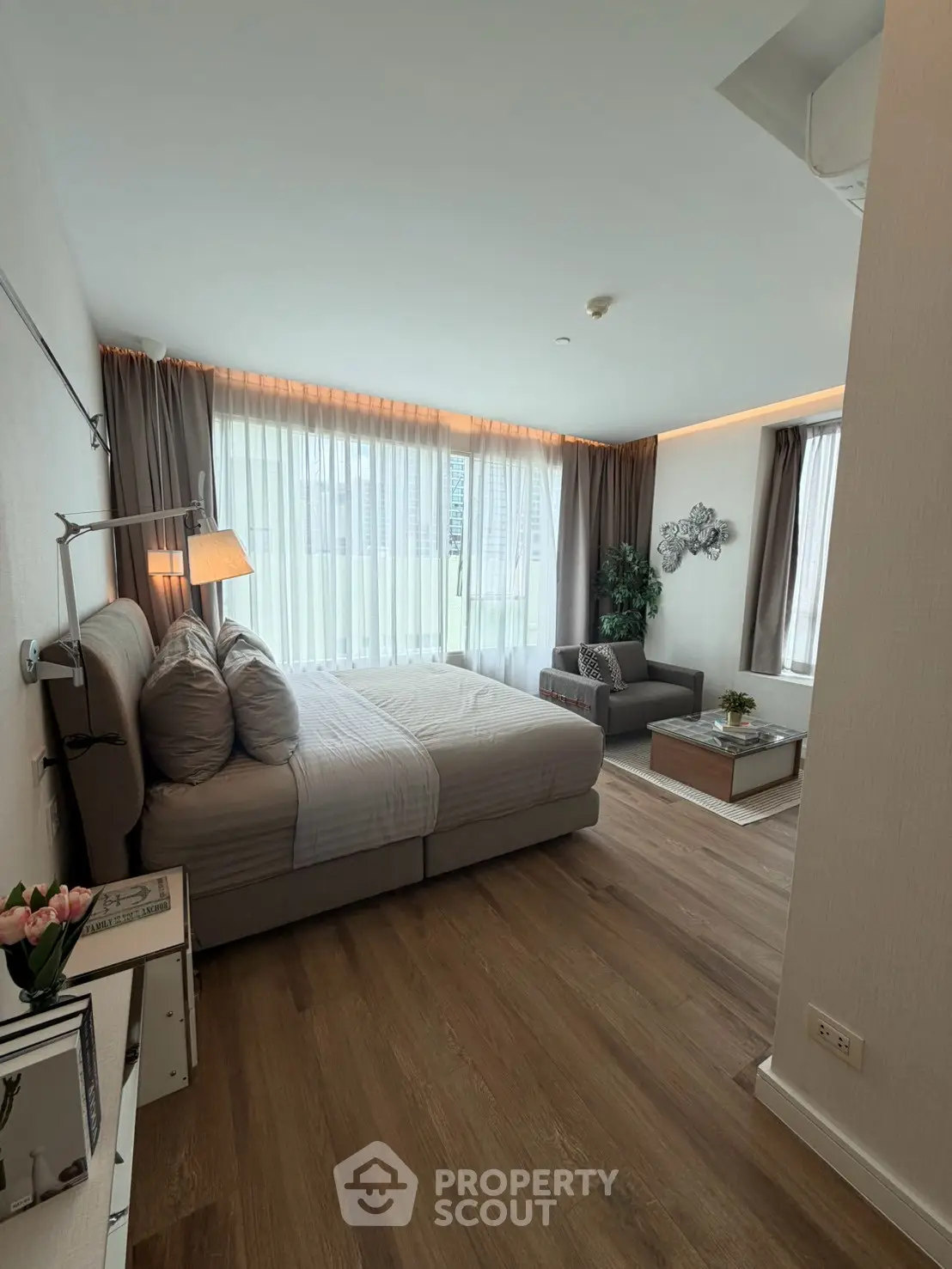 Spacious modern bedroom with large windows and cozy seating area