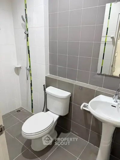 Modern bathroom with sleek design, featuring a shower, toilet, and pedestal sink in neutral tones.