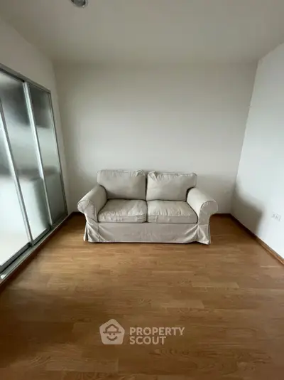 Minimalist room with a cozy white sofa and wooden flooring, perfect for a serene living space.