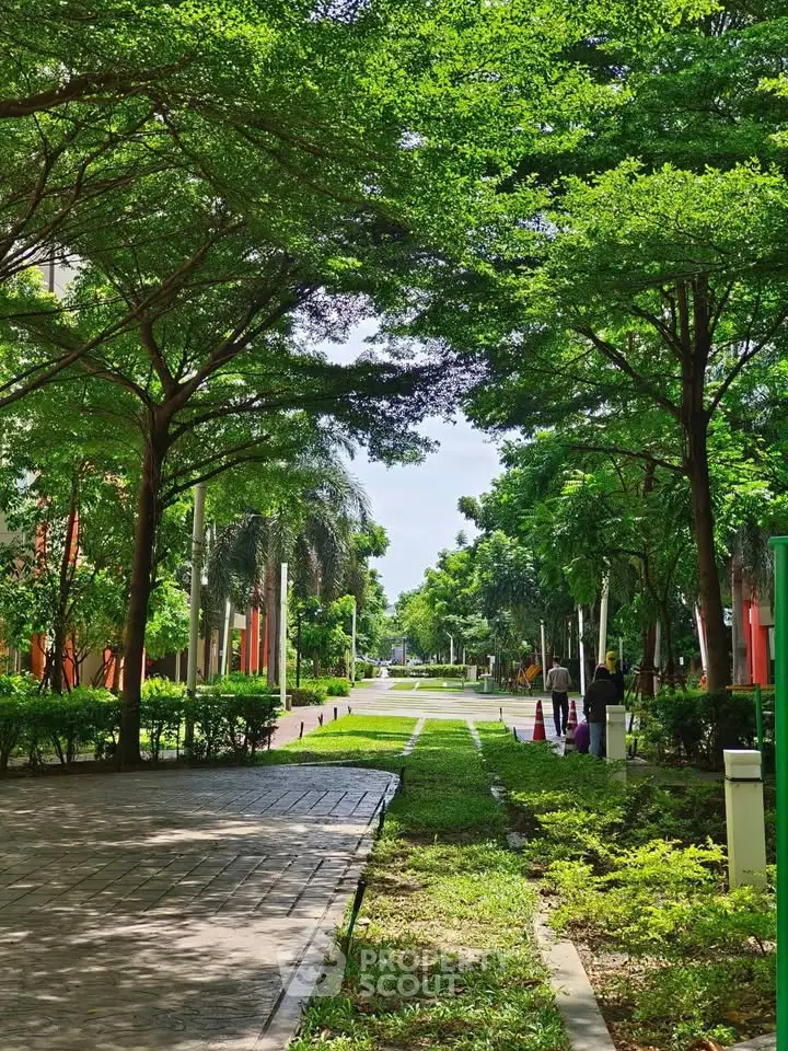 Lush green garden pathway in a residential complex with vibrant trees and serene ambiance.
