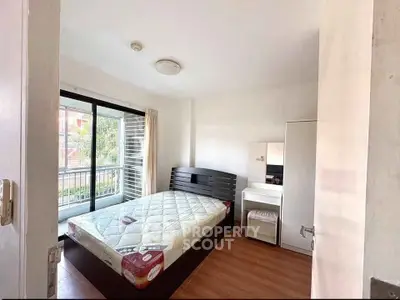 Bright bedroom with large window and modern furnishings, perfect for cozy living.