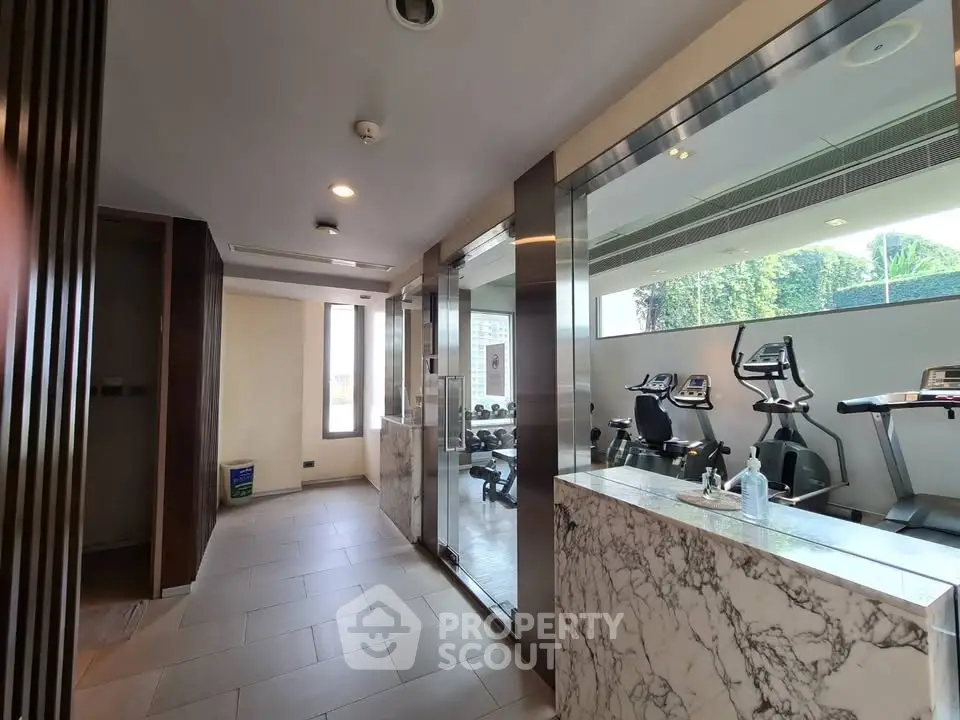 Modern gym with glass walls and exercise equipment in a luxury building