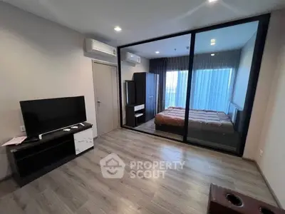 Modern apartment with glass-walled bedroom and sleek living area, featuring wood flooring and air conditioning.
