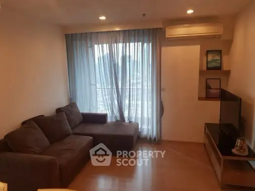 Cozy living room with large sofa and city view through sheer curtains