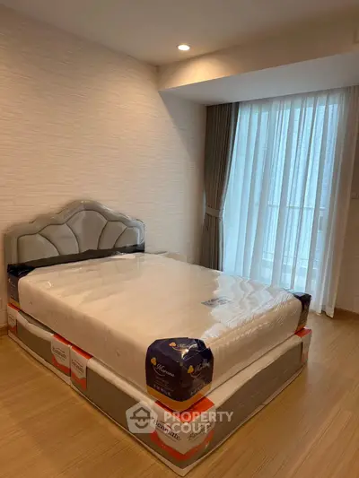 Modern bedroom with new mattress and stylish headboard, featuring floor-to-ceiling windows and elegant curtains.