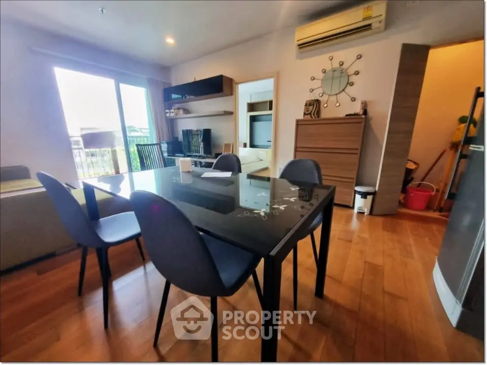 Modern dining area with sleek black table, stylish chairs, and wooden flooring in a bright apartment.