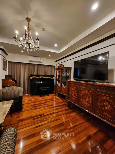Elegant living room with chandelier, polished wood floor, and classic furniture