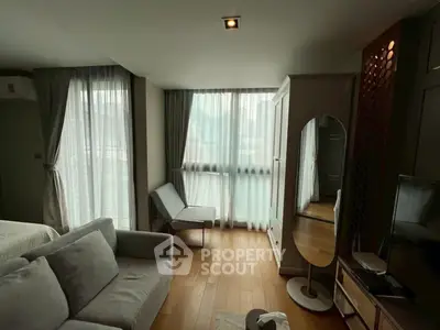 Modern living room with large windows, stylish furniture, and wooden flooring in a cozy apartment.