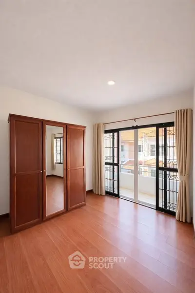 Spacious bedroom with wooden flooring and balcony access